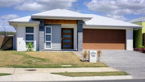 A modern two-story house with a garage, a stone accent wall, and a well-maintained lawn. - Pet Friendly, new House Peregian Breeze Drive, Peregian Beach (Peregian Beach)