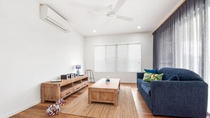 A modern living room with a blue sofa, wooden coffee table, and a small dog toy. - Pet Friendly, new House Peregian Breeze Drive, Peregian Beach (Peregian Beach)