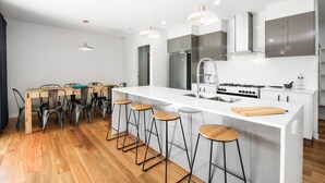 A modern kitchen with a central island, bar stools, stainless steel appliances, and pendant lighting. - Pet Friendly, new House Peregian Breeze Drive, Peregian Beach (Peregian Beach)