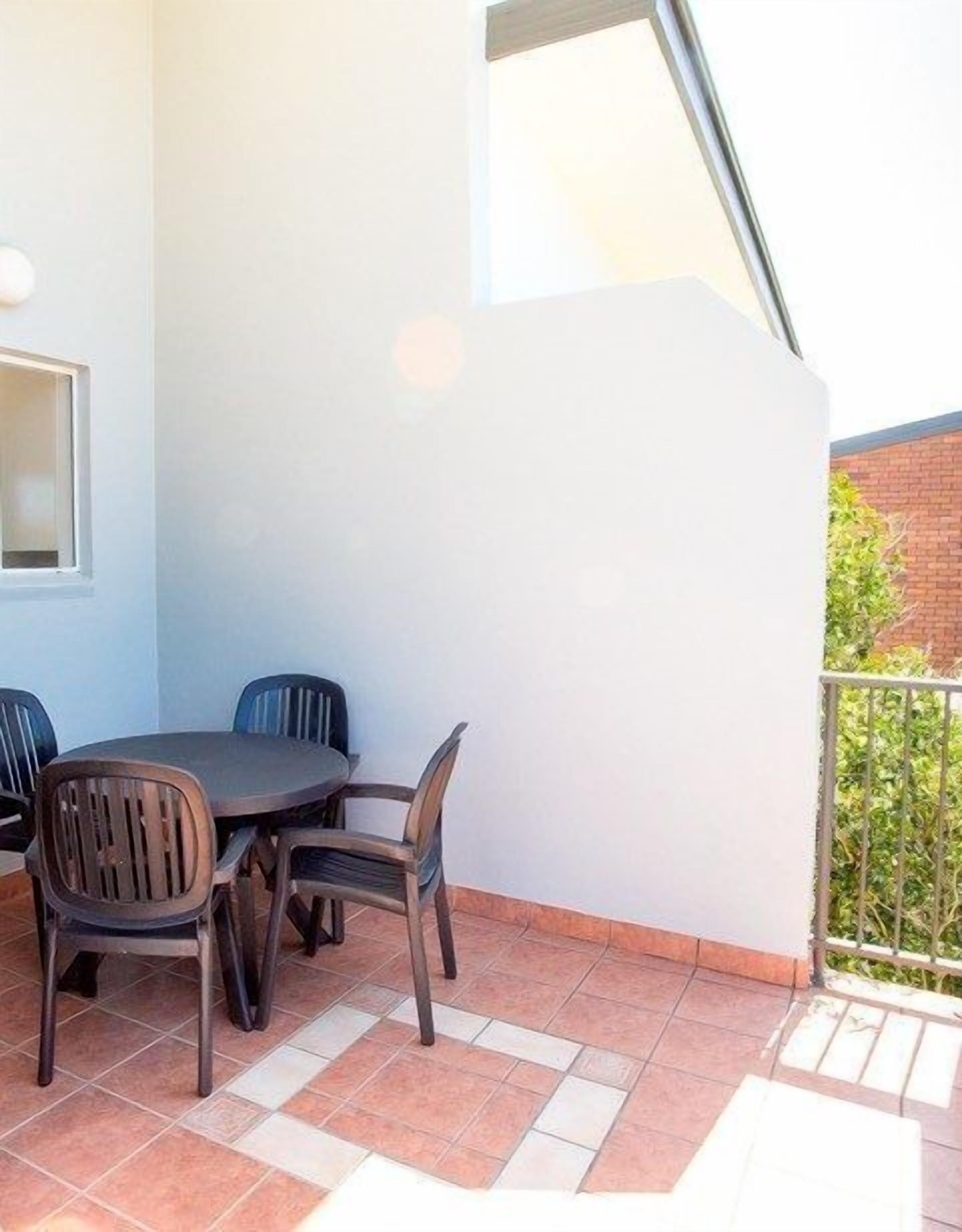 Une petite terrasse extérieure avec une table ronde et quatre chaises.
