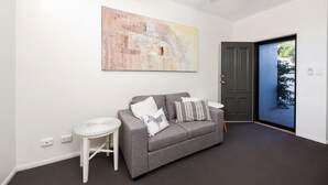 Een moderne woonkamer met een grijze bank, een witte bijzettafel en een groot abstract schilderij aan de muur.