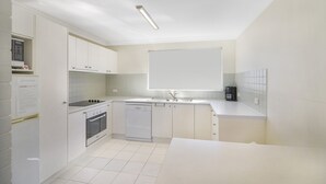 A modern kitchen with white cabinets, a stove, oven, dishwasher, and a large window above the sink. - Unit 3 at 4 Pelican Street, Peregian Beach, Noosa Shire (Peregian Beach)