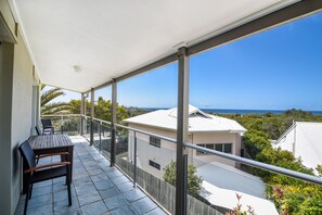Enjoy the ocean view from this balcony with a table and two chairs.