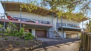 A modern two-story building with a curved roof, outdoor seating, and a covered staircase. - Peregian Beach House - 2/22 Avocet Parade (Peregian Beach)