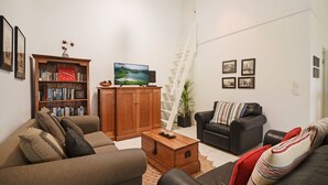 A living room with a sofa, a coffee table, a bookshelf, a TV, and a ladder. - Nobs -1/44 Peregian Esplanade (Peregian Beach)
