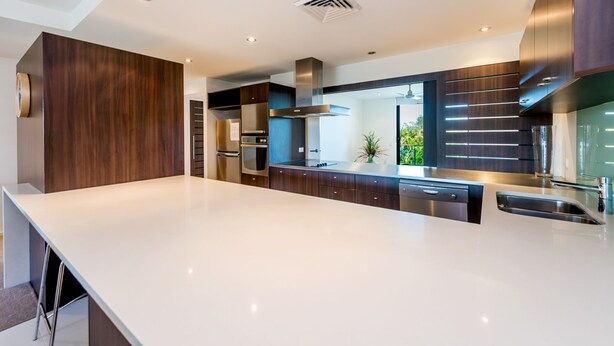 A modern kitchen with a large island, stainless steel appliances, and dark wood cabinetry.