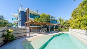 A modern building with a pool area, including a covered seating area and a clear swimming pool.