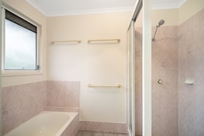 A bathroom with a bathtub, a shower, and three towel bars.