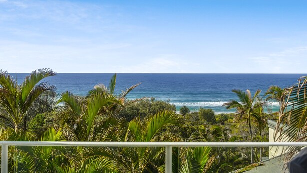 Un balcón con vistas al océano y vegetación tropical.