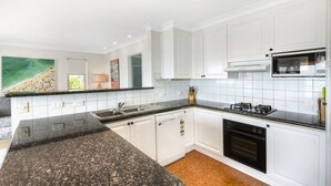 A modern kitchen with white cabinets, granite countertops, a built-in oven, and a microwave.