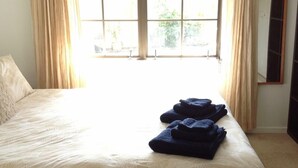 Een hotelkamer met een groot bed, beige gordijnen en uitzicht door het raam.