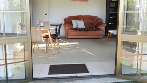 Een woonkamer met een bruine leren bank, een klein rond tafeltje en een boekenkast.
