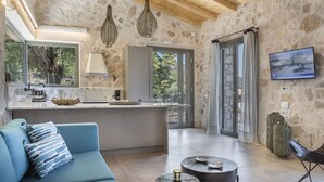 Une cuisine moderne avec un mur en pierre, un canapé bleu et un téléviseur fixé au mur.