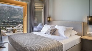 Une chambre d’hôtel avec un grand lit, une vue sur les montagnes et un balcon avec des sièges pour profiter de l’extérieur.