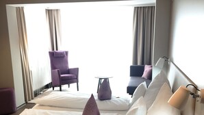 A hotel room with a large bed, a small table, a chair, and a desk. - Hotel Iris am See (Radolfzell am Bodensee)
