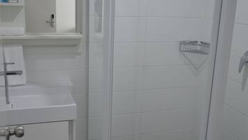 A bathroom with a white sink, mirror, and a glass-enclosed shower stall.