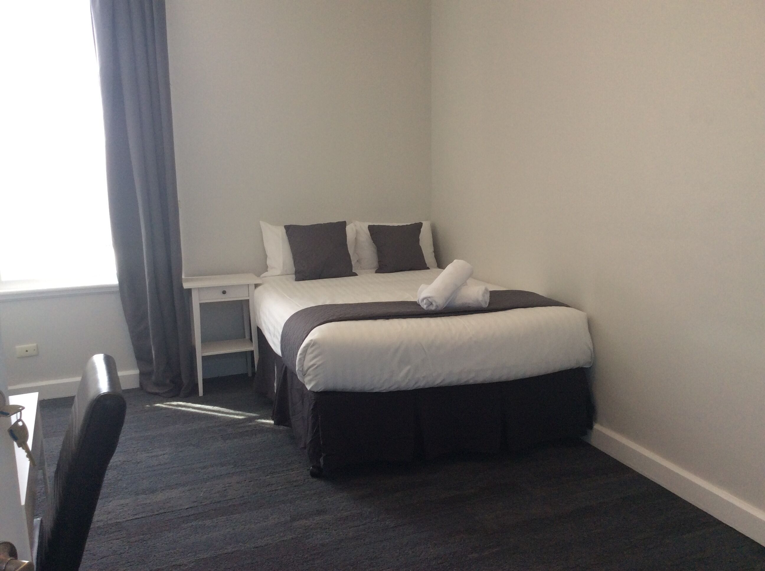 Una habitación de hotel con cama, escritorio y silla.
