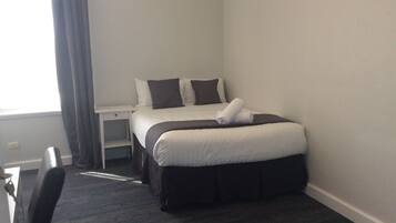 Una habitación de hotel con cama, escritorio y silla.