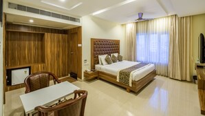 A hotel room with a bed, a desk, a chair, a TV, and a wardrobe. - Ostin Viceroy Grand (Guntur)