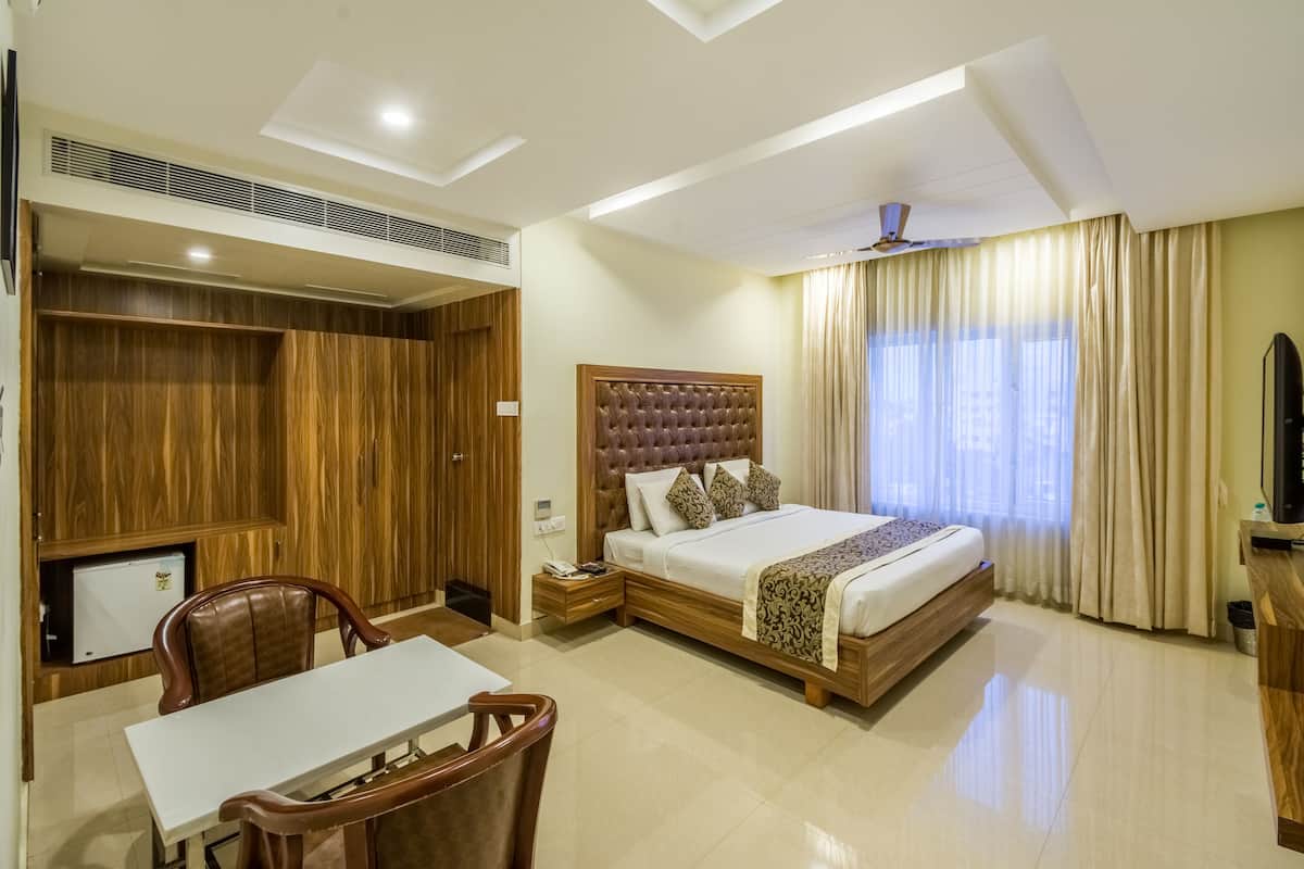 A hotel room with a bed, a desk, a chair, a TV, and a wardrobe.