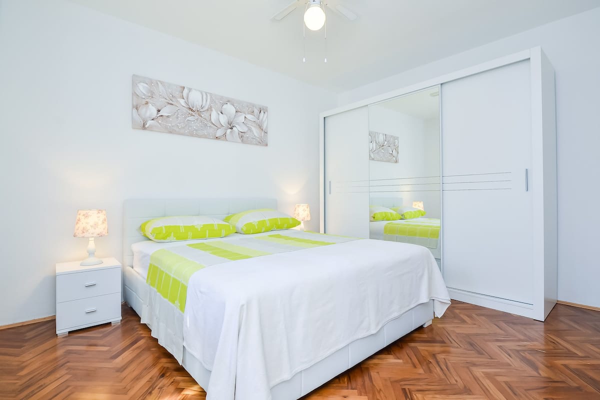 A bedroom with a bed, nightstand, and wardrobe.