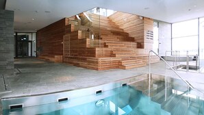 A modern indoor pool area with a wooden structure and glass railings. - Cape East (Haparanda)