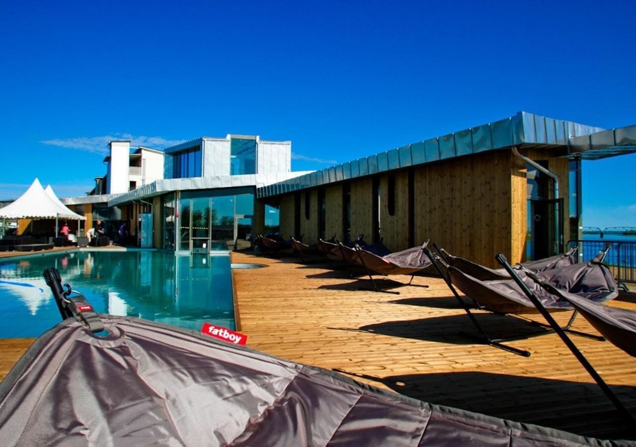 A poolside area with lounge chairs and a view of the ocean.