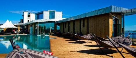 A poolside area with lounge chairs and a view of the ocean.
