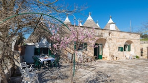 A stone building with arched doorways and a small table with chairs outside. - Stile e relax nei trulli by Wonderful Italy (Martina Franca)