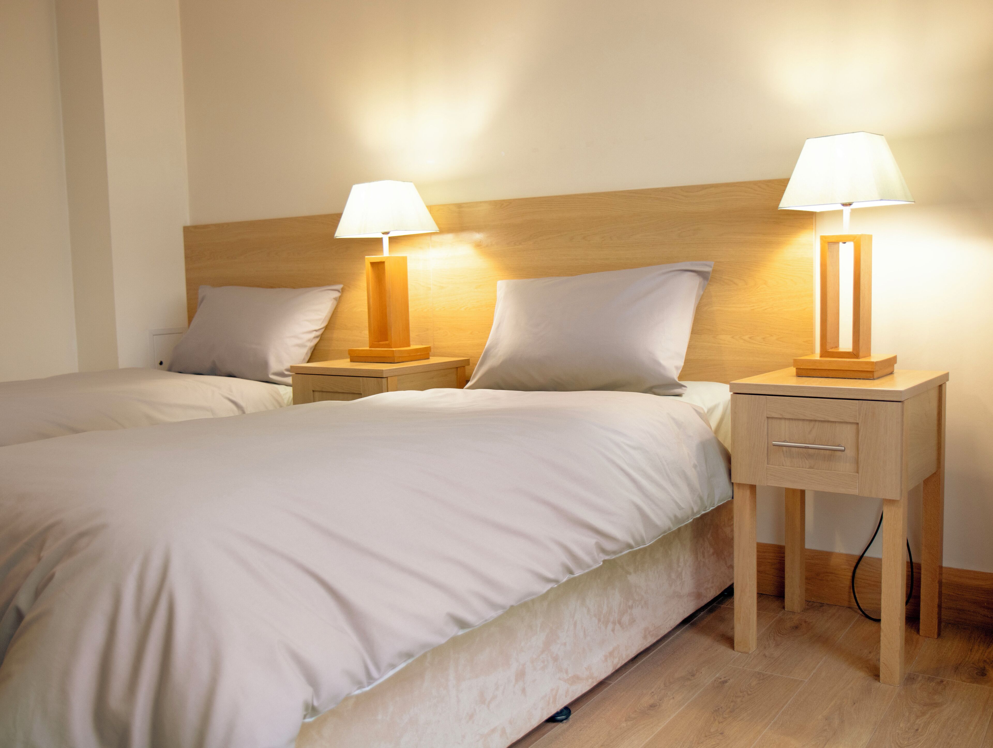 A neatly made double bed with two bedside tables, each with a lamp.