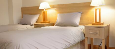 A neatly made double bed with two bedside tables, each with a lamp.