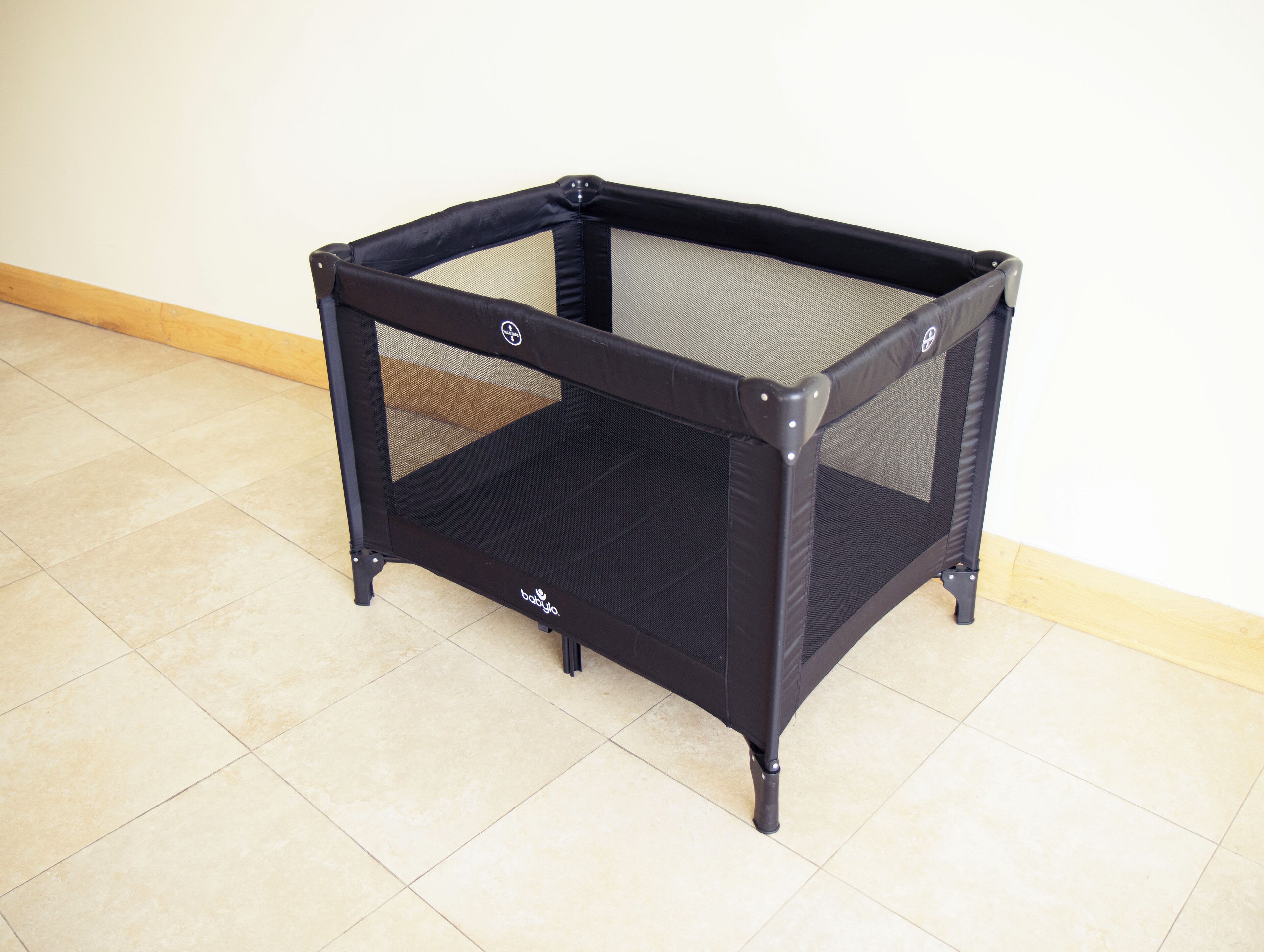 A black baby playpen with a mesh top and a logo on the front.