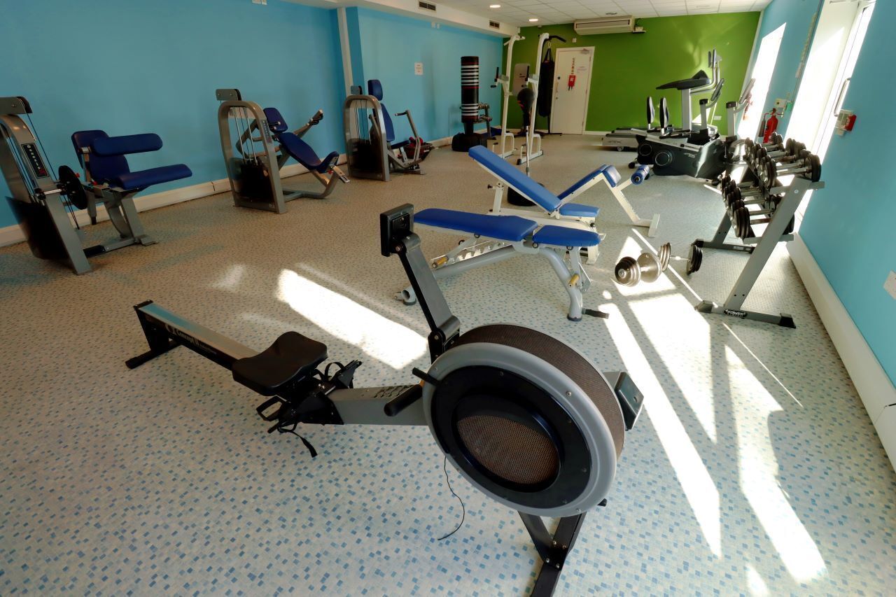 Ett gym med träningsutrustning, en blå vägg och en grön vägg.