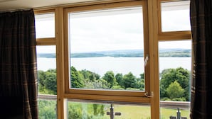 A room with a large window overlooking a lake and greenery.