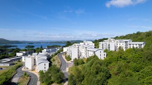 Moderni asuinkompleksi, jossa on useita rakennuksia, kaareva tie ja taustalla järvi.