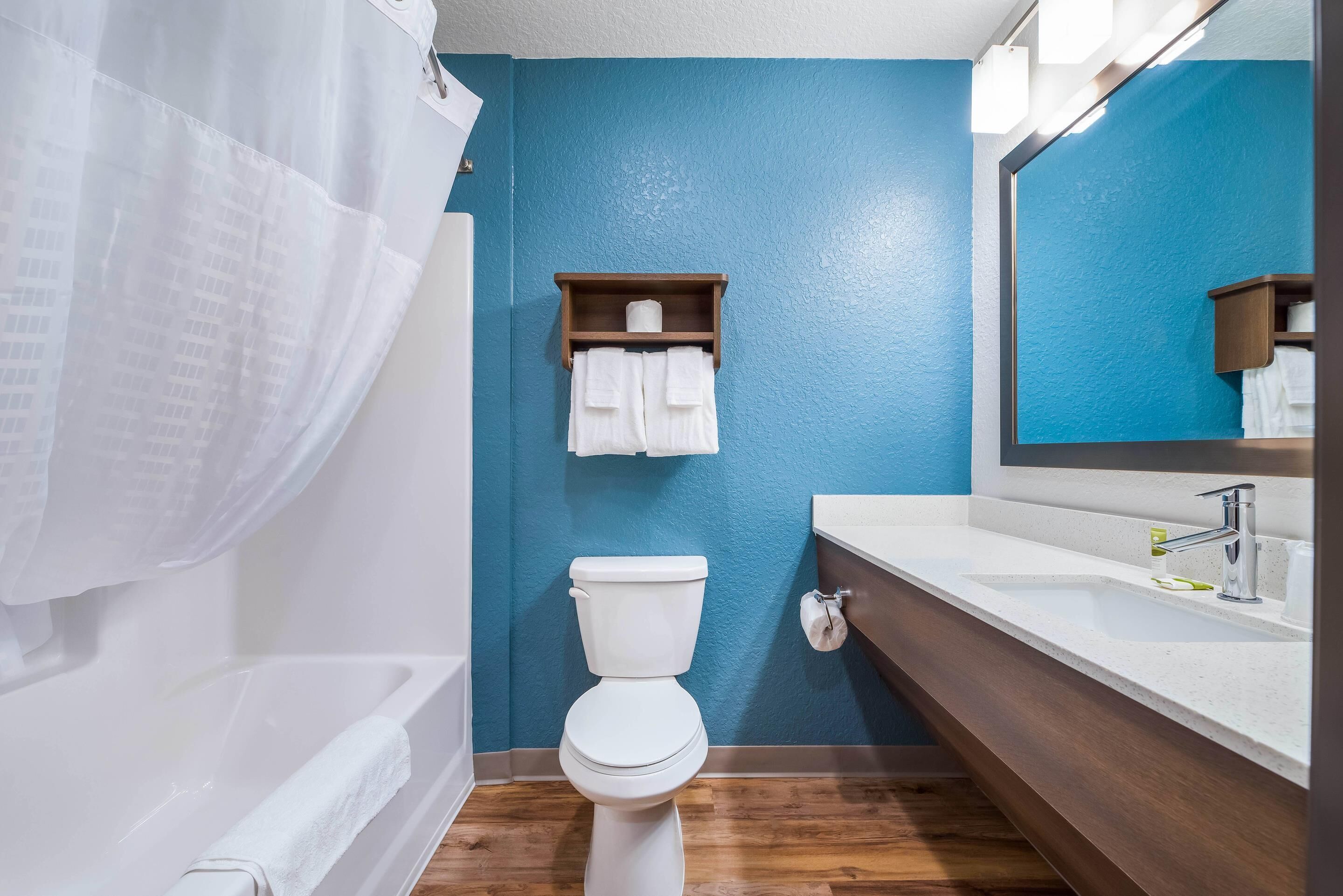 A bathroom with a toilet, sink, and mirror.