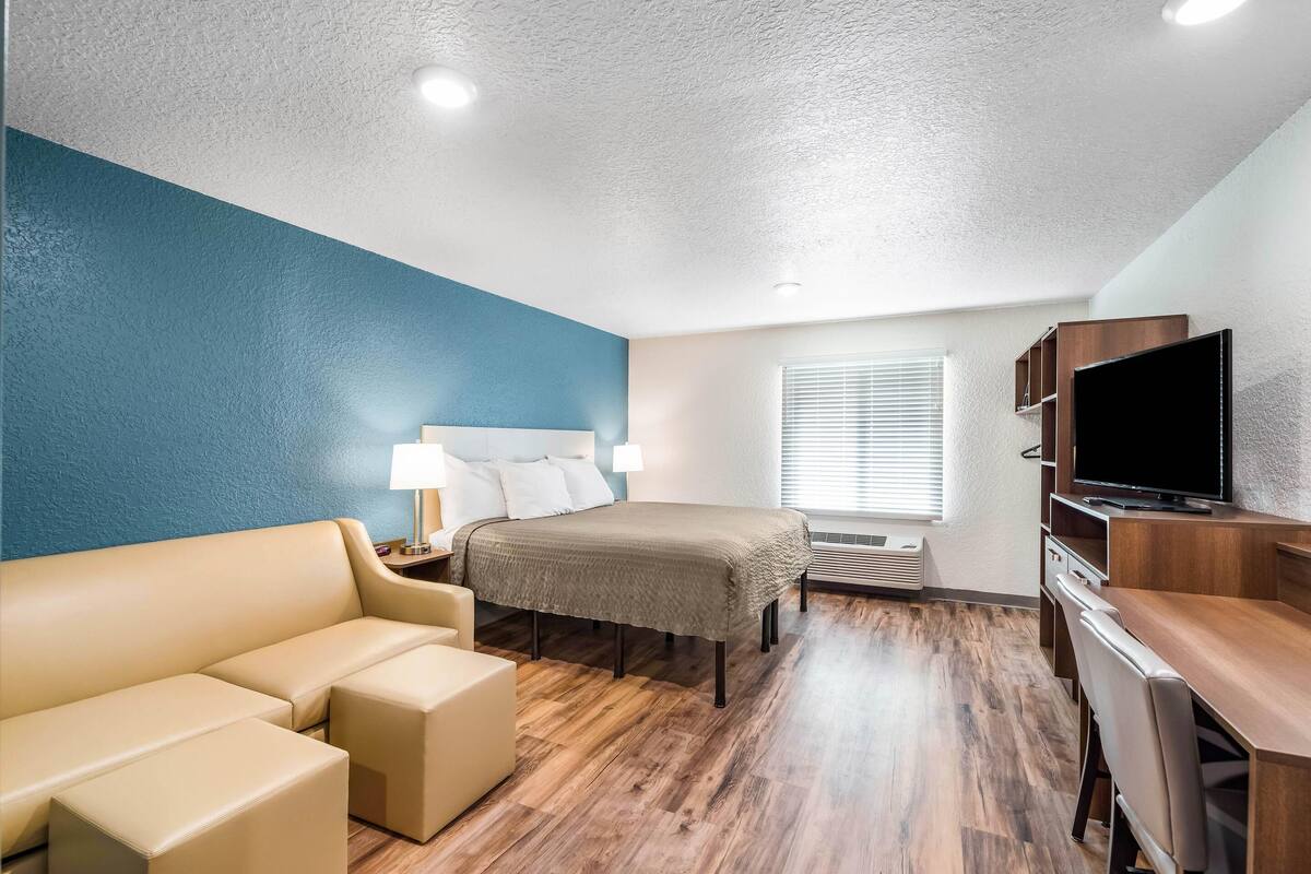 A hotel room with a bed, a sofa, a TV, and a desk.