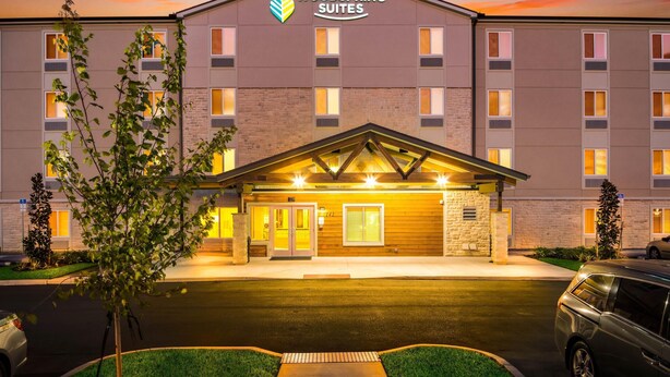 A hotel with a modern design, featuring a prominent logo and a well-lit entrance. - WoodSpring Suites Davenport FL (Davenport)