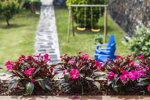 A garden with a stone pathway, a swing set, and a blue chair. - Vintage Charming House 1 (Ponta Delgada)