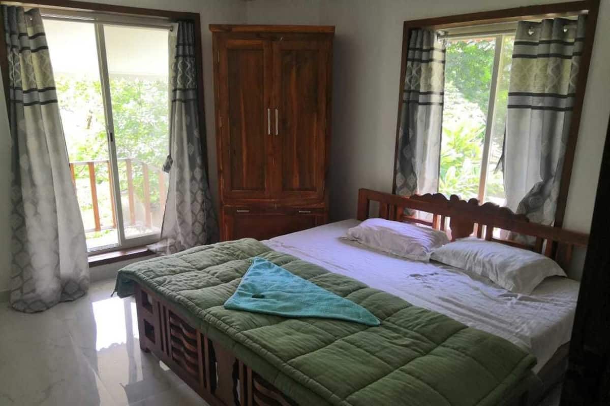 A bedroom with a bed, a wardrobe, and a window with curtains.