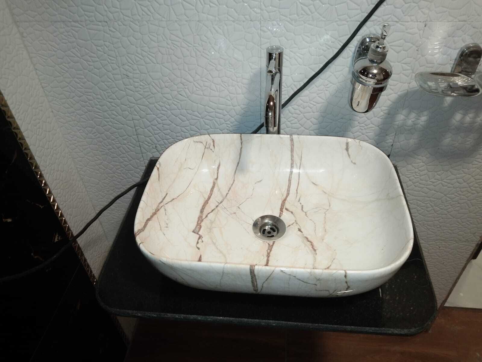 A bathroom with a white marble sink, a black countertop, and a textured wall.