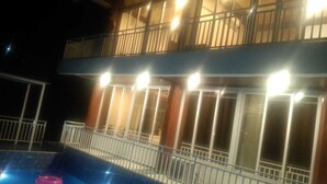 A two-story building with balconies, a swimming pool, and a well-lit exterior. - Ekdant Holiday Home (Murud)