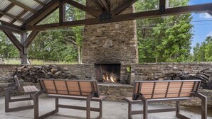 An outdoor seating area with benches facing a stone fireplace. - Bluff Cabin #5 -  Dual Masters, Game Room, Hot Tub, ADA access, NO Pet Cabin. (Kimberling City)
