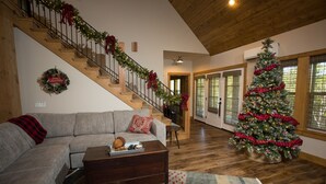 A spacious living room with a wooden staircase, a large Christmas tree, and a cozy sofa. - Bluff Cabin #5 -  Dual Masters, Game Room, Hot Tub, ADA access, NO Pet Cabin. (Kimberling City)