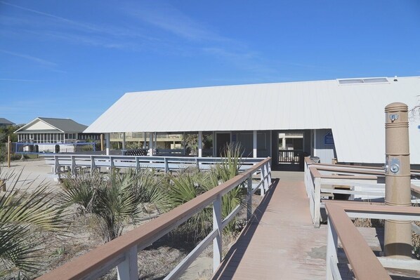 A boardwalk leading to a white building with a covered entrance.