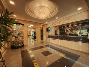 A reception area with a chandelier, a reception desk, and a display of shoes.