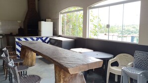 A rustic interior with a large wooden table, stone flooring, and a high ceiling. - Chácara Recanto do baiano (Sorocaba)