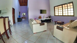 A spacious living area with two sofas, a coffee table, a TV, and a large window. - Chácara Recanto do baiano (Sorocaba)