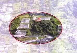 Une vue aérienne d’un quartier résidentiel avec de nombreuses maisons, un espace vert central et un bâtiment dont le toit est rouge.