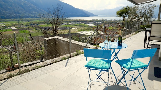 Eine Terrasse mit Tisch und Stühlen mit Blick auf ein malerisches Tal und einen See.
